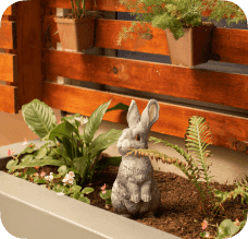 A bunny statue in a garden bed.