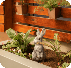 A bunny statue in a garden bed.